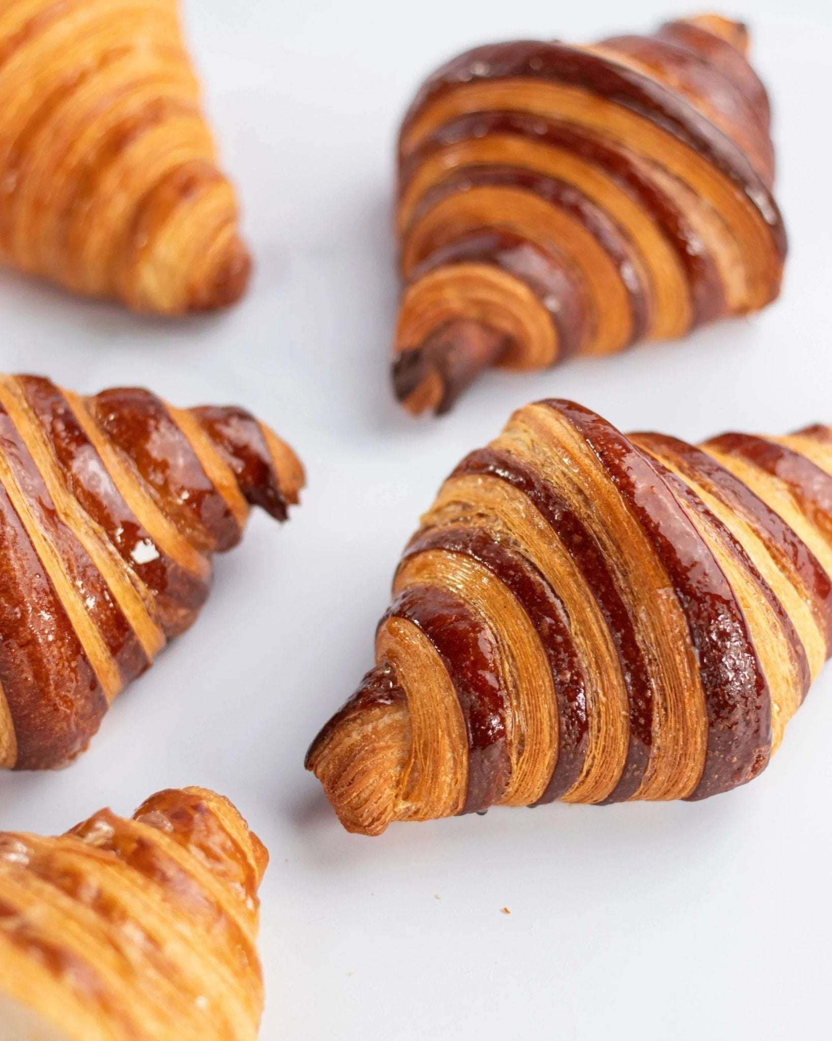 Gros plan de croissants au chocolat Maison Vatelier, dorés et glacés.