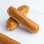 Deux éclairs au café Maison Vatelier avec un glaçage brillant sur fond blanc.