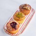 Assortiment de trois financiers Maison Vatelier, dont un à la pistache, sur un plateau rayé.