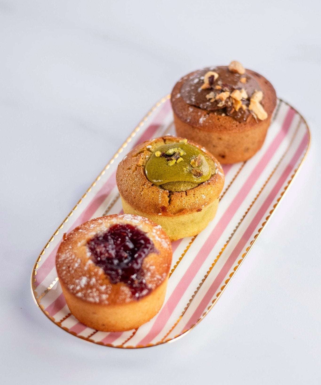 Assortiment de trois financiers Maison Vatelier, dont un à la pistache, sur un plateau rayé.