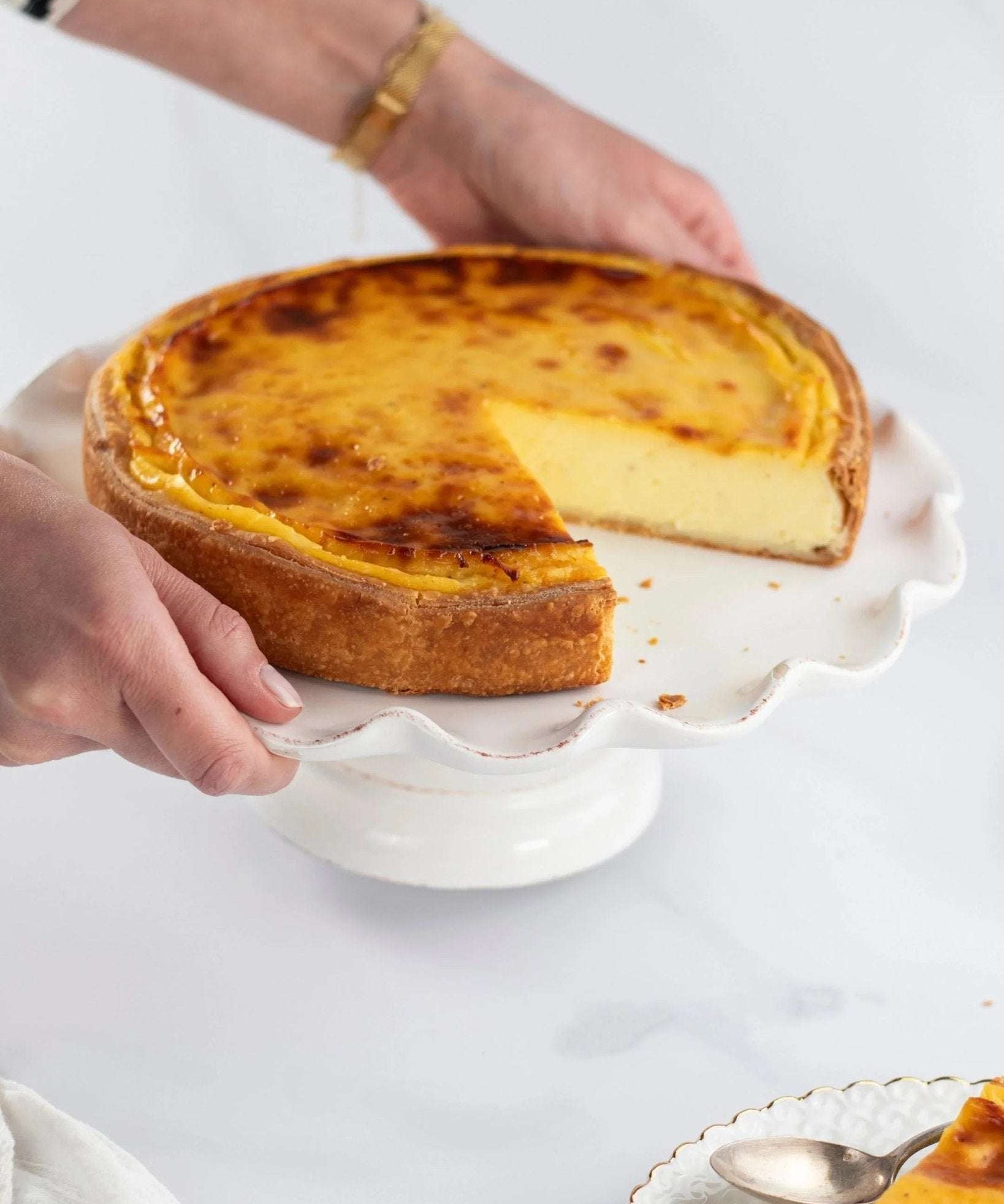 Flan vanille Maison Vatelier sur un support à gâteau blanc avec une part découpée