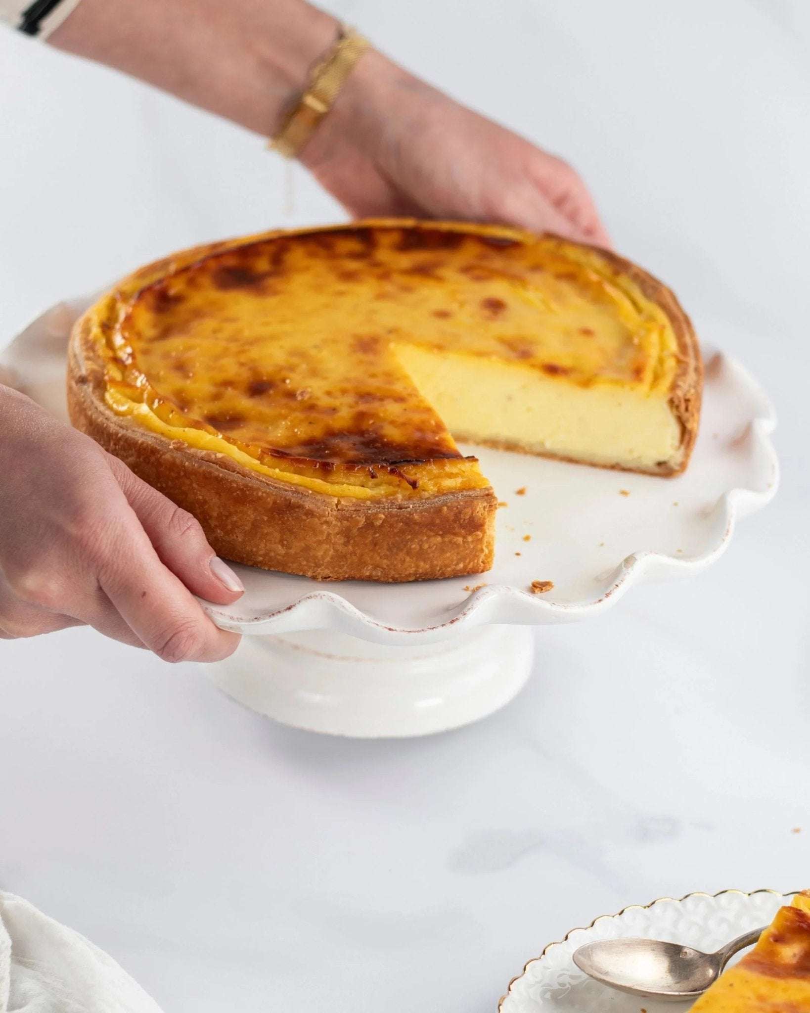 Flan vanille Maison Vatelier sur un support à gâteau blanc avec une part découpée