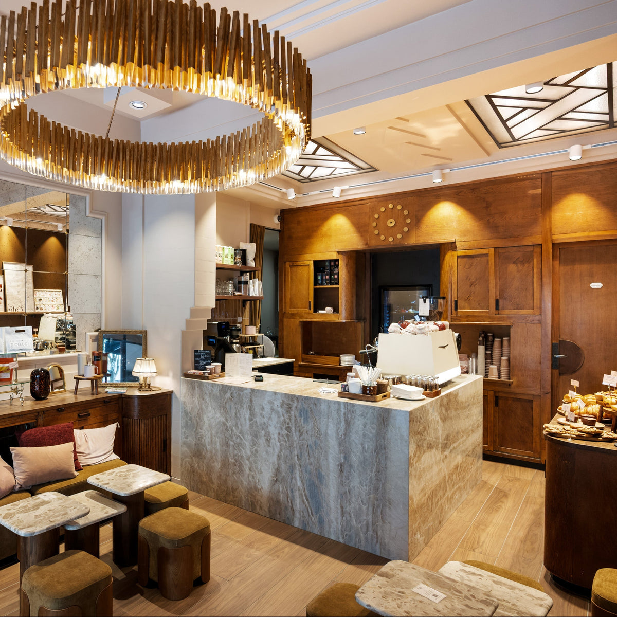 Intérieur luxueux d'une pâtisserie avec comptoir en marbre et lustre design en bois.
