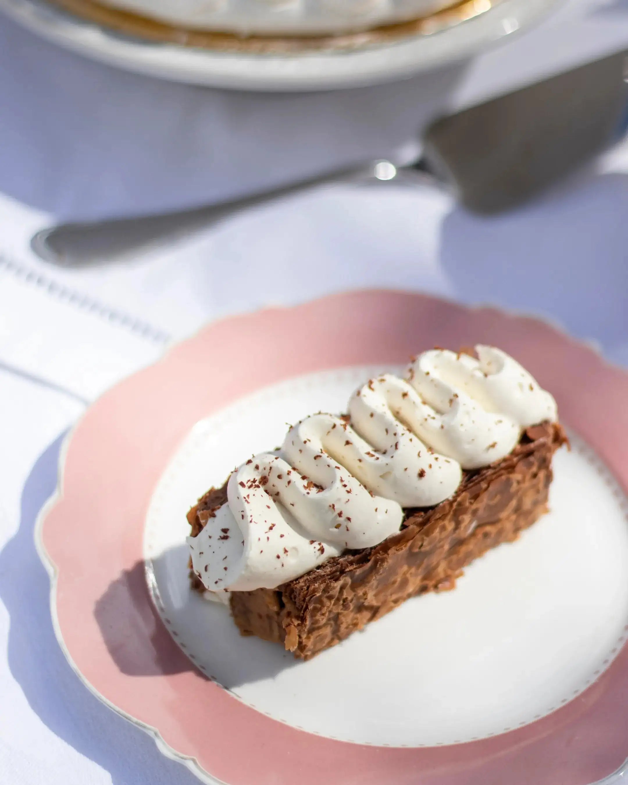 Part de Mille-Feuille praliné tonka Maison Vatelier avec crème chantilly sur assiette rose