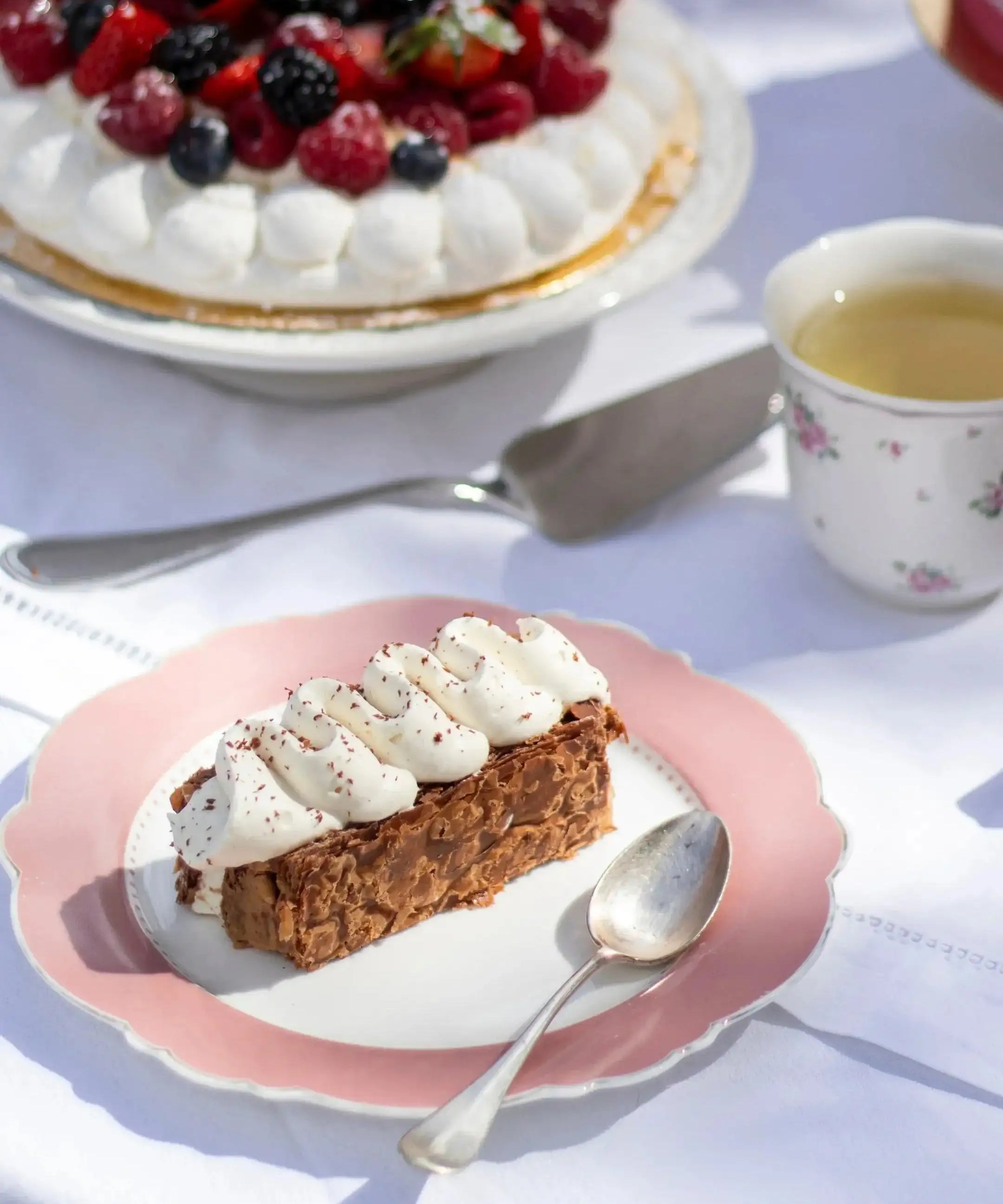 Part de Mille-Feuille praliné tonka de Maison Vatelier avec crème fouettée sur assiette rose.