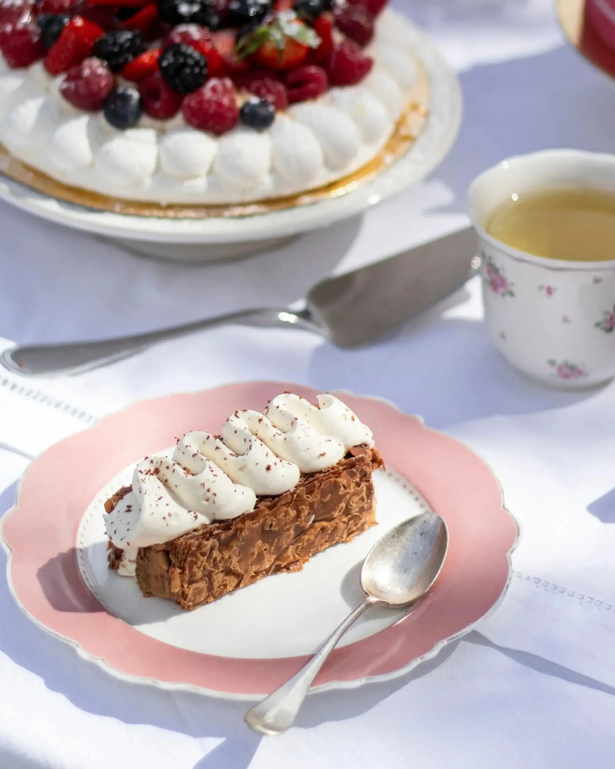 Part de Mille-Feuille praliné tonka de Maison Vatelier avec crème fouettée sur assiette rose.