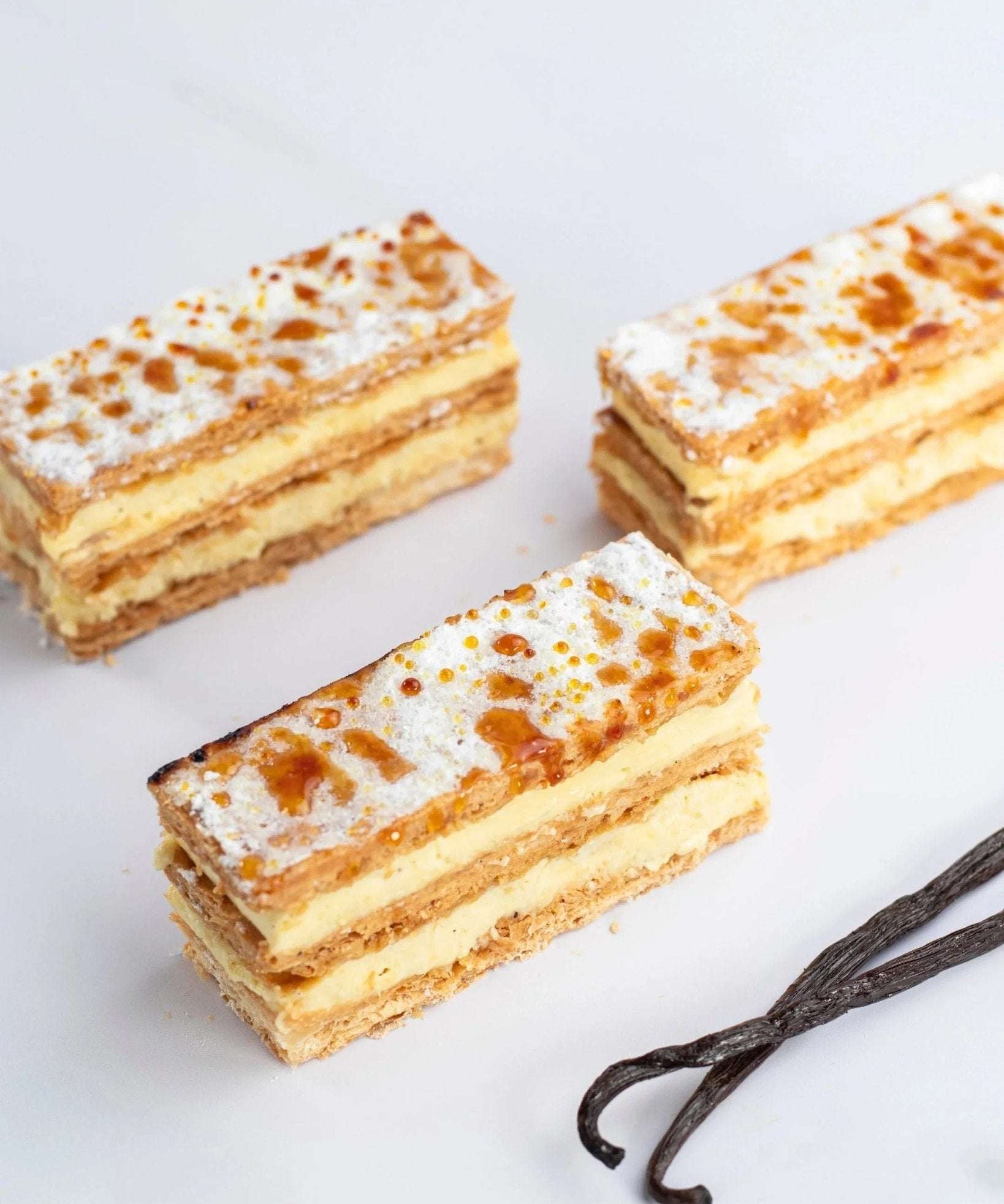 Trois millefeuilles à la vanille Maison Vatelier avec sucre glace et gousses de vanille.