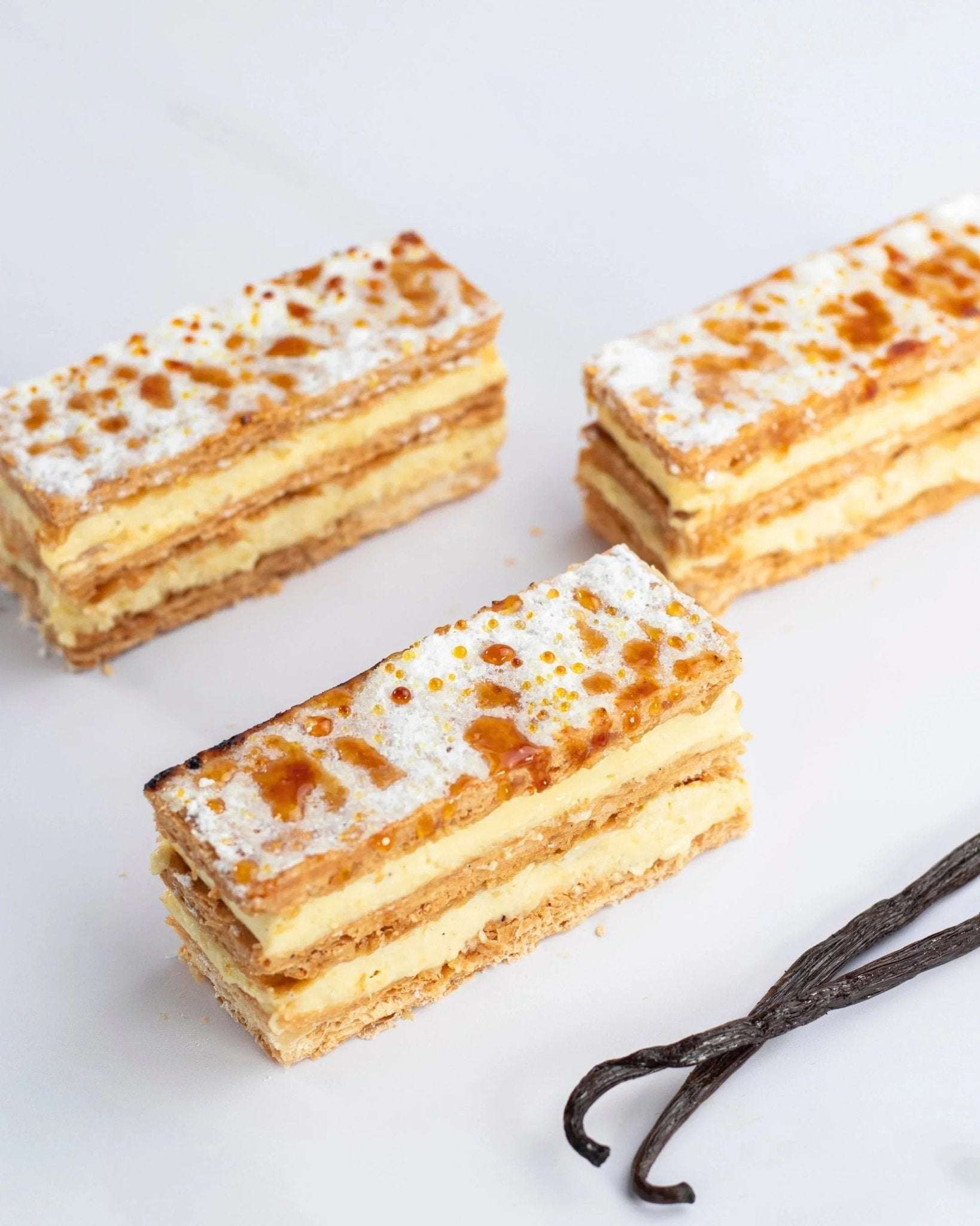Trois millefeuilles à la vanille Maison Vatelier avec sucre glace et gousses de vanille.