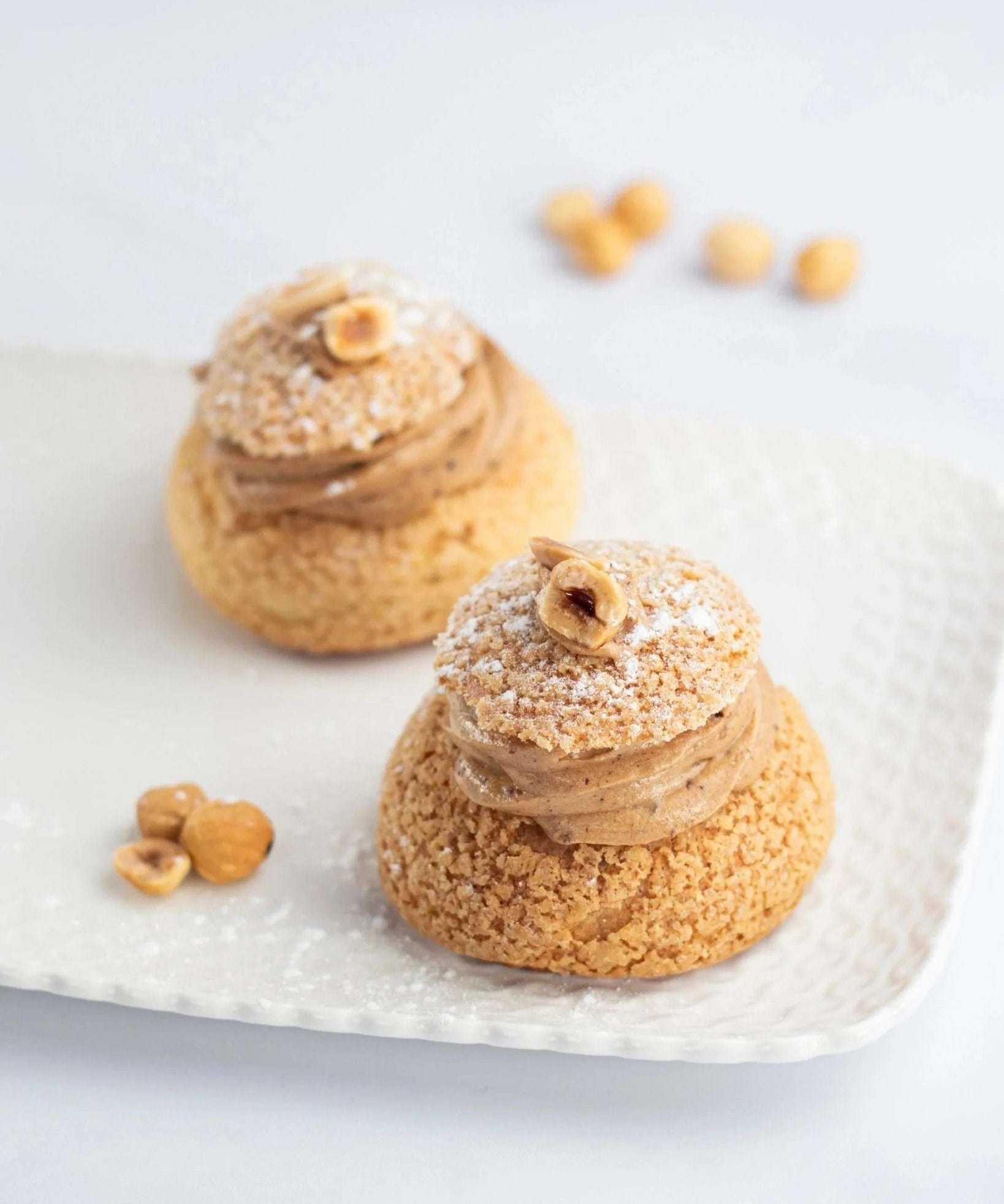 Deux Paris Brest Maison Vatelier garnies de crème praliné et décorées de noisettes.