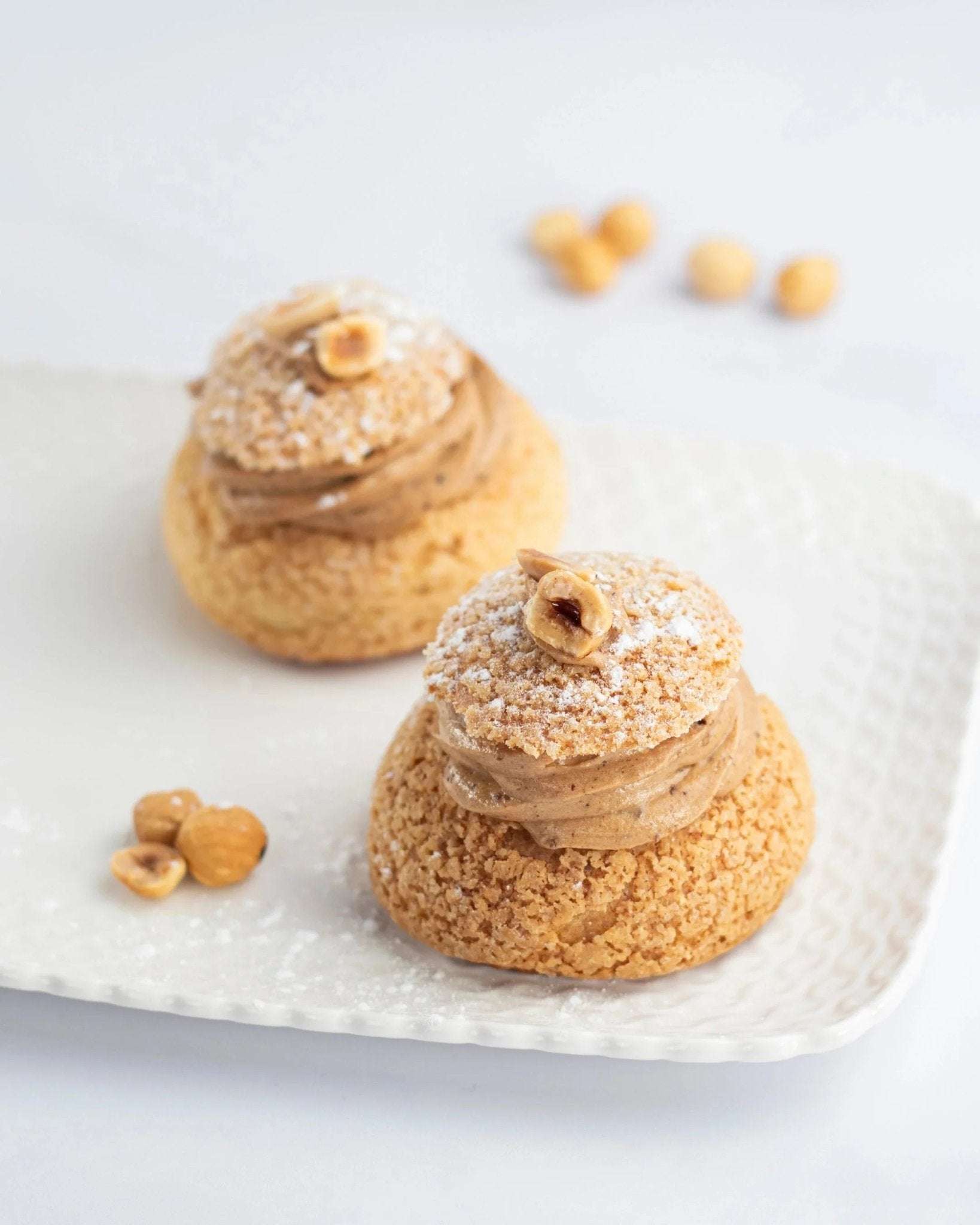 Deux Paris Brest Maison Vatelier garnies de crème praliné et décorées de noisettes.
