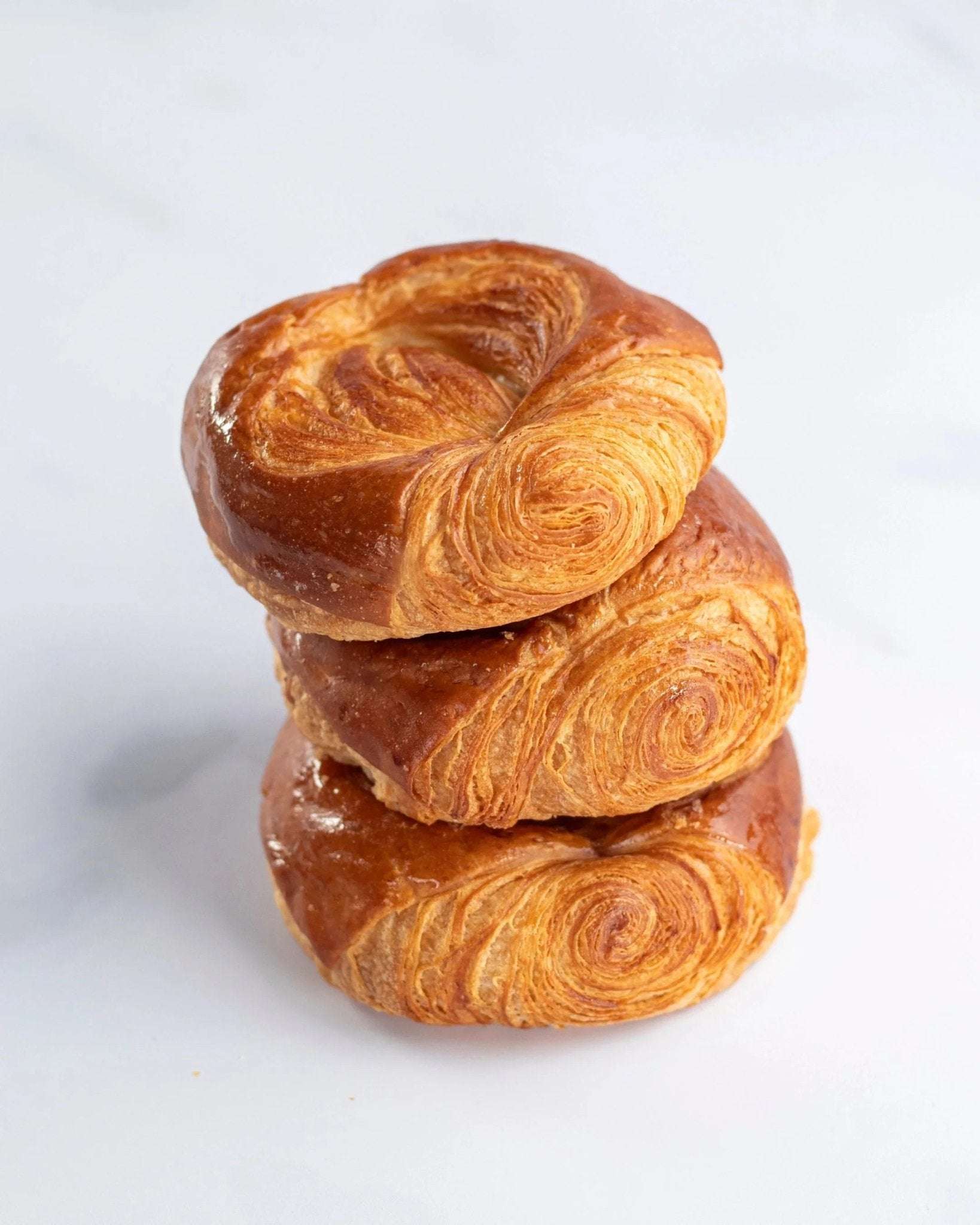 Pile de trois roulettes feuilletées dorées Maison Vatelier sur fond blanc.
