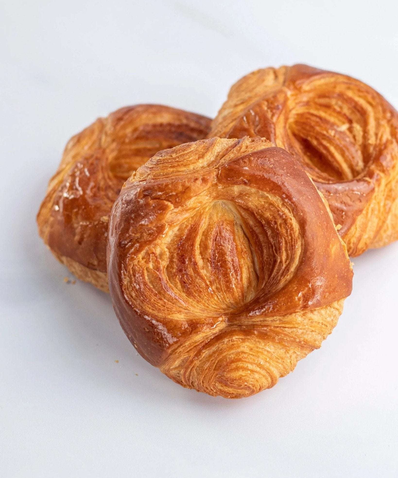 Trois roulettes feuilletées dorées de Maison Vatelier sur fond blanc.