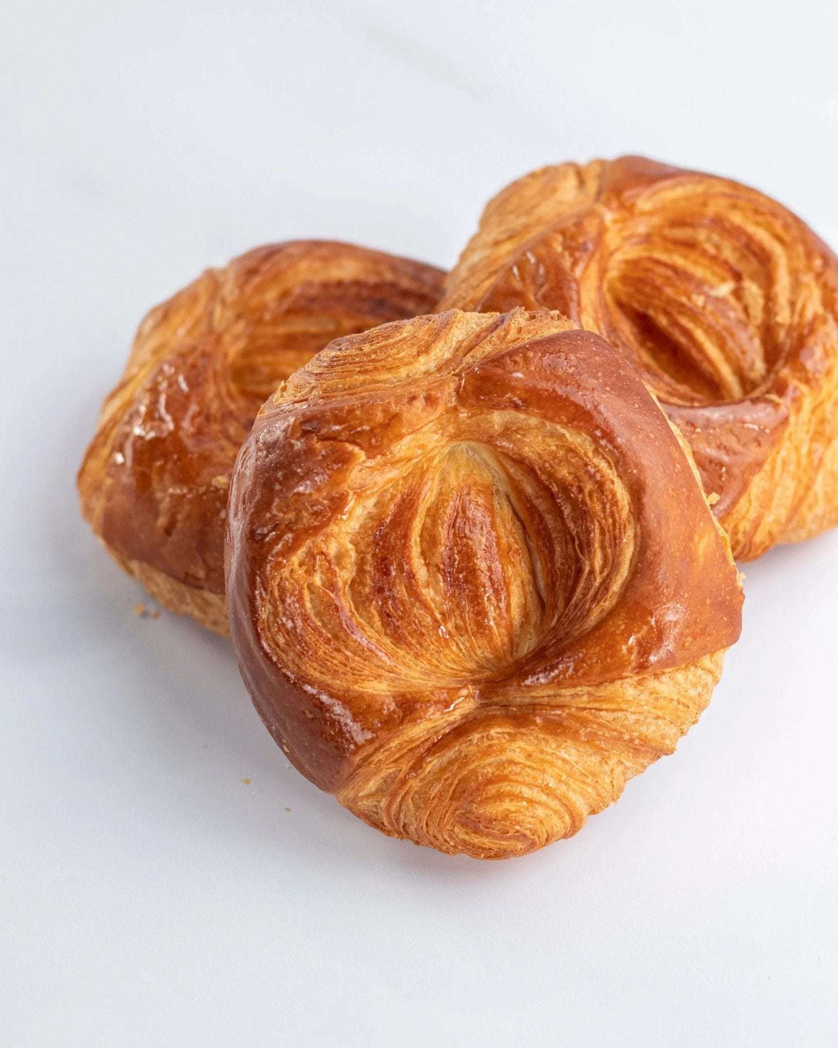 Trois roulettes feuilletées dorées de Maison Vatelier sur fond blanc.