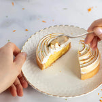 Une part de tarte au citron meringuée sur une assiette blanche avec une cuillère.