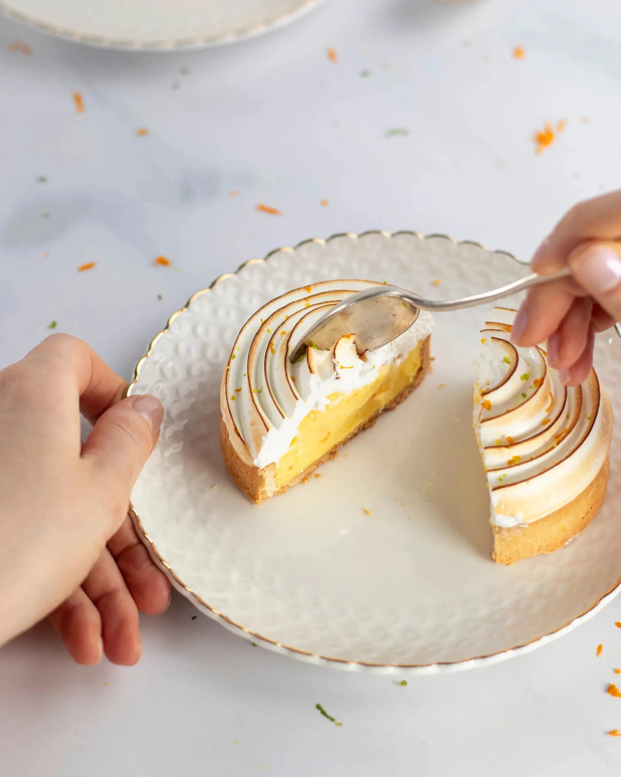 Une part de tarte au citron meringuée sur une assiette blanche avec une cuillère.