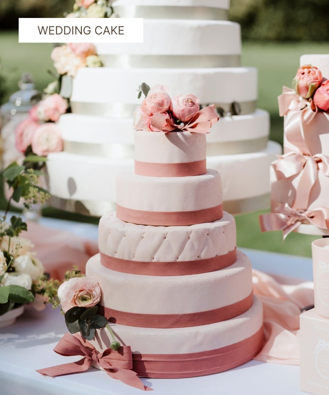 Pièce montée de mariage blanche et rose poudré décorée de fleurs fraîches.